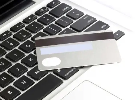 Foto di una porzione di tastiera di un notebook con sopra appoggiata una carta di credito con la parte posteriore con la barra magnetica rivolta verso l'alto.